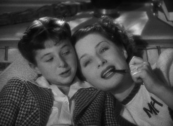 Movie still from “The Women” (1939), directed by George Cukor – A woman and a boy are laying on a bed; Close Up shot, High angle