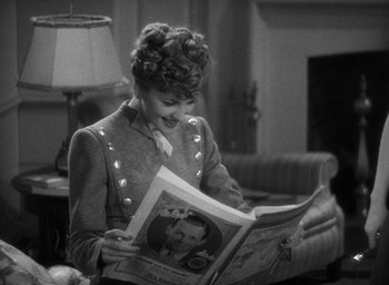 Movie still from “The Women” (1939), directed by George Cukor – A woman reading a newspaper in a living room; Medium shot, Over the shoulder angle