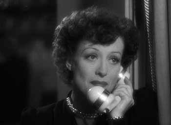 Movie still from “The Women” (1939), directed by George Cukor – An older woman talking on a phone while wearing a necklace; Close Up shot, High angle