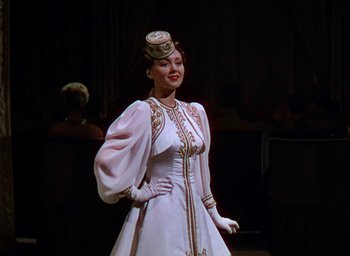 Movie still from “The Women” (1939), directed by George Cukor – A woman in a white dress and a top hat; Medium shot, Low angle