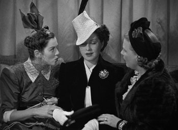 Movie still from “The Women” (1939), directed by George Cukor – A group of women in hats and a dress; Medium shot, High angle