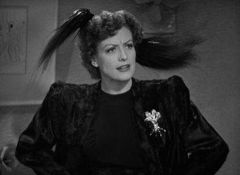 Movie still from “The Women” (1939), directed by George Cukor – An old photo of a woman in a black jacket with a feather in her hair; Close Up shot, High angle