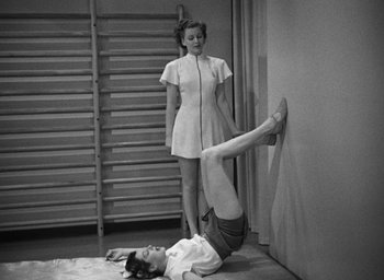 Movie still from “The Women” (1939), directed by George Cukor – A woman standing next to another woman in a room; Wide shot, Low angle
