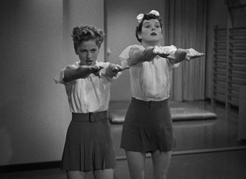 Movie still from “The Women” (1939), directed by George Cukor – Two young girls are holding a bow and arrow; Medium shot, Low angle