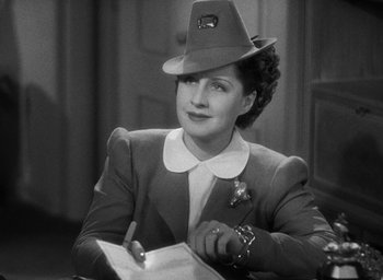 Movie still from “The Women” (1939), directed by George Cukor – A woman wearing a hat is writing on a piece of paper; Close Up shot, High angle
