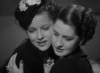 Movie still from “The Women” (1939), directed by George Cukor – Two beautiful young women embracing each other in a black and white photo; Close Up shot, Low angle