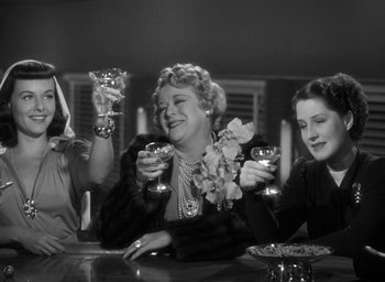 Movie still from “The Women” (1939), directed by George Cukor – A group of women sitting at a table with wine glasses; Medium shot, Low angle