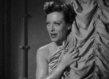 Movie still from “The Women” (1939), directed by George Cukor – A black - and - white photo of a woman holding a drape; Close Up shot, Low angle