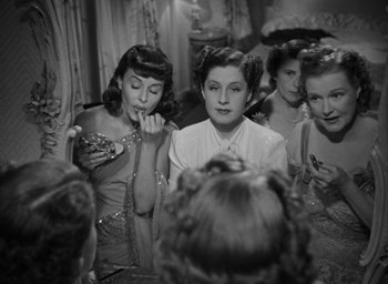 Movie still from “The Women” (1939), directed by George Cukor – A black and white photo of a group of women sitting in front of a mirror; Medium shot, High angle