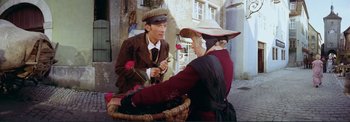 Movie still from “The Wonderful World of the Brothers Grimm” (1962), directed by Henry Levin – A man and a woman holding roses in front of a basket; Medium shot, High angle