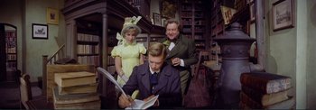 Movie still from “The Wonderful World of the Brothers Grimm” (1962), directed by Henry Levin – Two women and a young man in a library; Medium shot, High angle