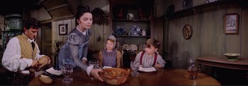Movie still from “The Wonderful World of the Brothers Grimm” (1962), directed by Henry Levin – Three children sitting at a table with a bowl of food; Medium shot, High angle