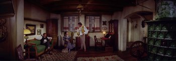 Movie still from “The Wonderful World of the Brothers Grimm” (1962), directed by Henry Levin – A man and a woman sitting in a living room next to each other; Wide shot, High angle