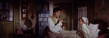 Movie still from “The Wonderful World of the Brothers Grimm” (1962), directed by Henry Levin – A man holding a pipe in his mouth while holding a dog; Medium shot, Overhead angle