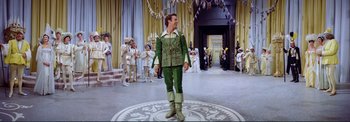 Movie still from “The Wonderful World of the Brothers Grimm” (1962), directed by Henry Levin – A man dressed in green stands in a circle of costumed people; Wide shot, High angle