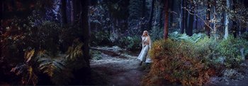 Movie still from “The Wonderful World of the Brothers Grimm” (1962), directed by Henry Levin – A woman in a white dress standing in the woods; Wide shot, High angle