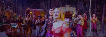 Movie still from “The Wonderful World of the Brothers Grimm” (1962), directed by Henry Levin – A man and a woman are standing next to each other in front of other people; Medium shot, Low angle