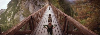 Movie still from “The Wonderful World of the Brothers Grimm” (1962), directed by Henry Levin – A woman laying on the ground on top of a wooden bridge; Wide shot, Overhead angle