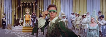 Movie still from “The Wonderful World of the Brothers Grimm” (1962), directed by Henry Levin – A man wearing a green mask while holding a phone; Medium shot, Low angle