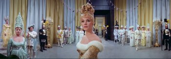 Movie still from “The Wonderful World of the Brothers Grimm” (1962), directed by Henry Levin – A woman in a gold dress and a fur trimmed headpiece; Close Up shot, Low angle