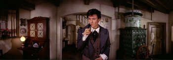 Movie still from “The Wonderful World of the Brothers Grimm” (1962), directed by Henry Levin – A man in a suit and tie holding a drink; Medium shot, High angle