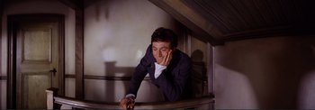 Movie still from “The Wonderful World of the Brothers Grimm” (1962), directed by Henry Levin – A man leaning on a railing writing on a piece of paper; Medium shot, High angle