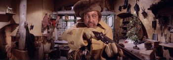 Movie still from “The Wonderful World of the Brothers Grimm” (1962), directed by Henry Levin – A man in a fur hat holding a gun in a room; Medium shot, Low angle