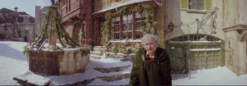 Movie still from “The Wonderful World of the Brothers Grimm” (1962), directed by Henry Levin – An older woman standing in front of a building; Wide shot, Low angle