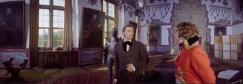 Movie still from “The Wonderful World of the Brothers Grimm” (1962), directed by Henry Levin – A man standing next to a statue in a room; Medium shot, Low angle