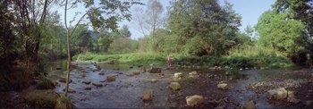 Movie still from “The Wonderful World of the Brothers Grimm” (1962), directed by Henry Levin – A person standing in a stream near rocks; Extreme Wide shot, High angle
