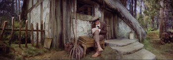 Movie still from “The Wonderful World of the Brothers Grimm” (1962), directed by Henry Levin – A man sitting on top of a wooden bench; Wide shot, High angle