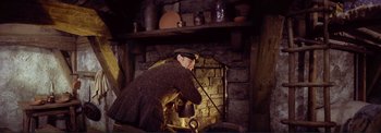 Movie still from “The Wonderful World of the Brothers Grimm” (1962), directed by Henry Levin – An old man is standing in front of a fireplace; Medium shot, High angle