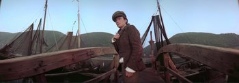 Movie still from “The Wonderful World of the Brothers Grimm” (1962), directed by Henry Levin – A man wearing a hat standing on top of a boat; Medium shot, Low angle