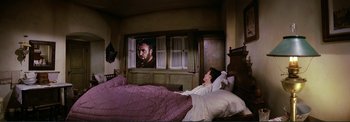 Movie still from “The Wonderful World of the Brothers Grimm” (1962), directed by Henry Levin – A person in a bed watching a man on a television screen; Wide shot, High angle