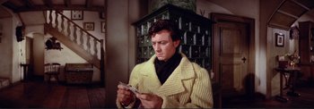 Movie still from “The Wonderful World of the Brothers Grimm” (1962), directed by Henry Levin – A man in a yellow sweater holding money; Medium shot, Low angle