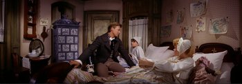 Movie still from “The Wonderful World of the Brothers Grimm” (1962), directed by Henry Levin – A man sitting on a bed next to a child; Medium shot, High angle