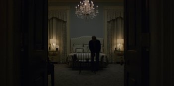Movie still from “House of Cards” (2013), created by Beau Willimon – A man standing in front of a bed in a bedroom; Wide shot, Low angle