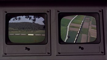 Movie still from “The Wrecking Crew” (1968), directed by Phil Karlson – A view from a train window of a field and a road; Extreme Wide shot, High angle