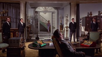 Movie still from “The Wrecking Crew” (1968), directed by Phil Karlson – A man laying on a chair in a living room; Wide shot, Low angle