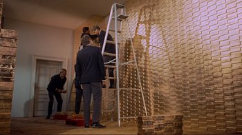 Movie still from “The Wrecking Crew” (1968), directed by Phil Karlson – A group of people standing around a brick wall; Wide shot, Low angle