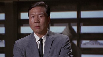 Movie still from “The Wrecking Crew” (1968), directed by Phil Karlson – An asian man in a suit and tie; Close Up shot, Low angle