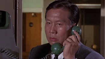 Movie still from “The Wrecking Crew” (1968), directed by Phil Karlson – A man holding a phone up to his ear; Close Up shot, Low angle