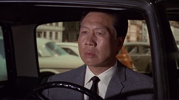 Movie still from “The Wrecking Crew” (1968), directed by Phil Karlson – A man wearing a suit and tie driving a car; Close Up shot, Low angle
