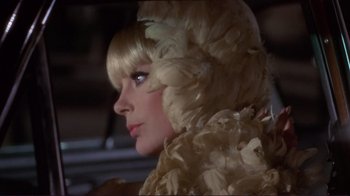 Movie still from “The Wrecking Crew” (1968), directed by Phil Karlson – A woman with blonde hair wearing a white dress and feathers; Close Up shot, Over the shoulder angle