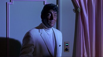 Movie still from “The Wrecking Crew” (1968), directed by Phil Karlson – A man in a white suit standing next to a purple curtain; Medium shot, Low angle