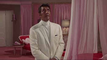 Movie still from “The Wrecking Crew” (1968), directed by Phil Karlson – A man in a white suit standing next to a pink curtain; Medium shot, Low angle