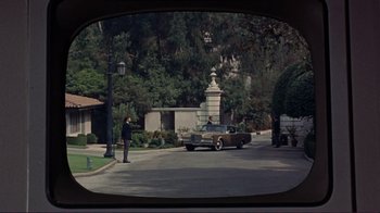 Movie still from “The Wrecking Crew” (1968), directed by Phil Karlson – A man standing on the side of a road next to a car; Extreme Wide shot, High angle