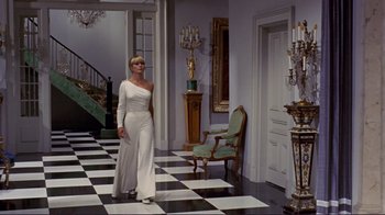 Movie still from “The Wrecking Crew” (1968), directed by Phil Karlson – A woman in a white dress standing in a room; Wide shot, Low angle