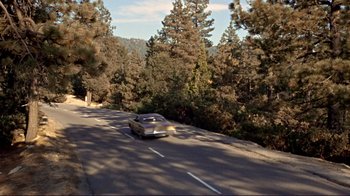 Movie still from “The Wrecking Crew” (1968), directed by Phil Karlson – A car driving down a road near a wooded area; Extreme Wide shot, High angle