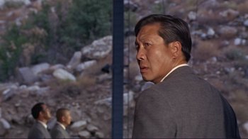 Movie still from “The Wrecking Crew” (1968), directed by Phil Karlson – A person wearing a suit and tie; Close Up shot, Over the shoulder angle